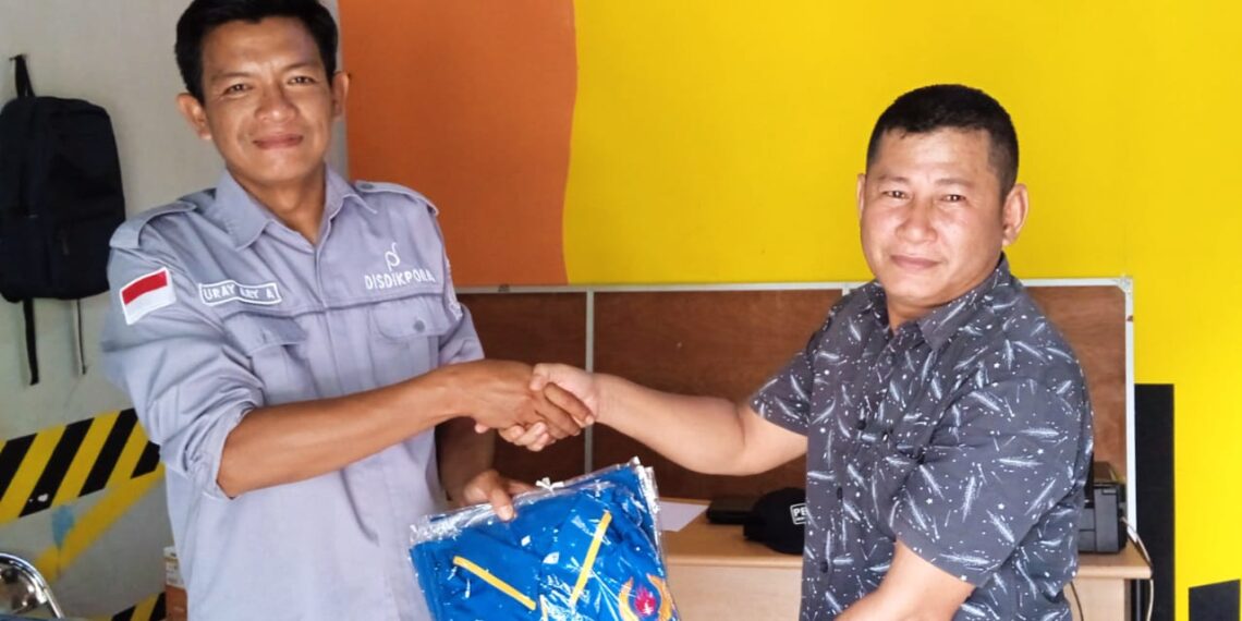 Kabid Olahraga Uray Ary Affandi saat menyerahkan baju ke ketua KONI Anambas Muslim