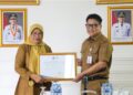 Kepala Diskominfo Kepri menyerahkan rekomendasi Integrasi TTE pada aplikasi SIPANGKAS kepada Kepala BKAD Provinsi Kepulauan Riau Venni Meitaria Detiawati di Collaboration Room Diskominfo Kepri, Senin (9/2/2026).