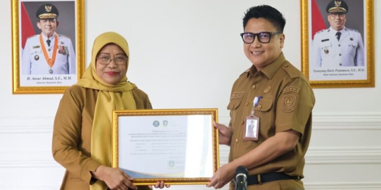 Kepala Diskominfo Kepri menyerahkan rekomendasi Integrasi TTE pada aplikasi SIPANGKAS kepada Kepala BKAD Provinsi Kepulauan Riau Venni Meitaria Detiawati di Collaboration Room Diskominfo Kepri, Senin (9/2/2026).